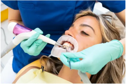 Un dentista della Parodontologia Coppede Medical Hub Roma in camice blu usa gli strumenti dentali per curare un paziente, che è sdraiato con un apribocca in posizione.