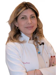 La Dott.ssa Valentina Prece del Coppedè Medical Hub di Roma, una donna dai capelli biondi lunghi fino alle spalle con un camice bianco, si erge sicura di sé con le braccia incrociate e un caldo sorriso su un semplice sfondo bianco.
