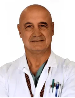 Prof. Valentino Valentini - Coppedè Medical Hub di Roma, un uomo di mezza età con la testa calva, in piedi con le braccia incrociate, camice bianco e stetoscopio, penne in tasca, su uno sfondo bianco.